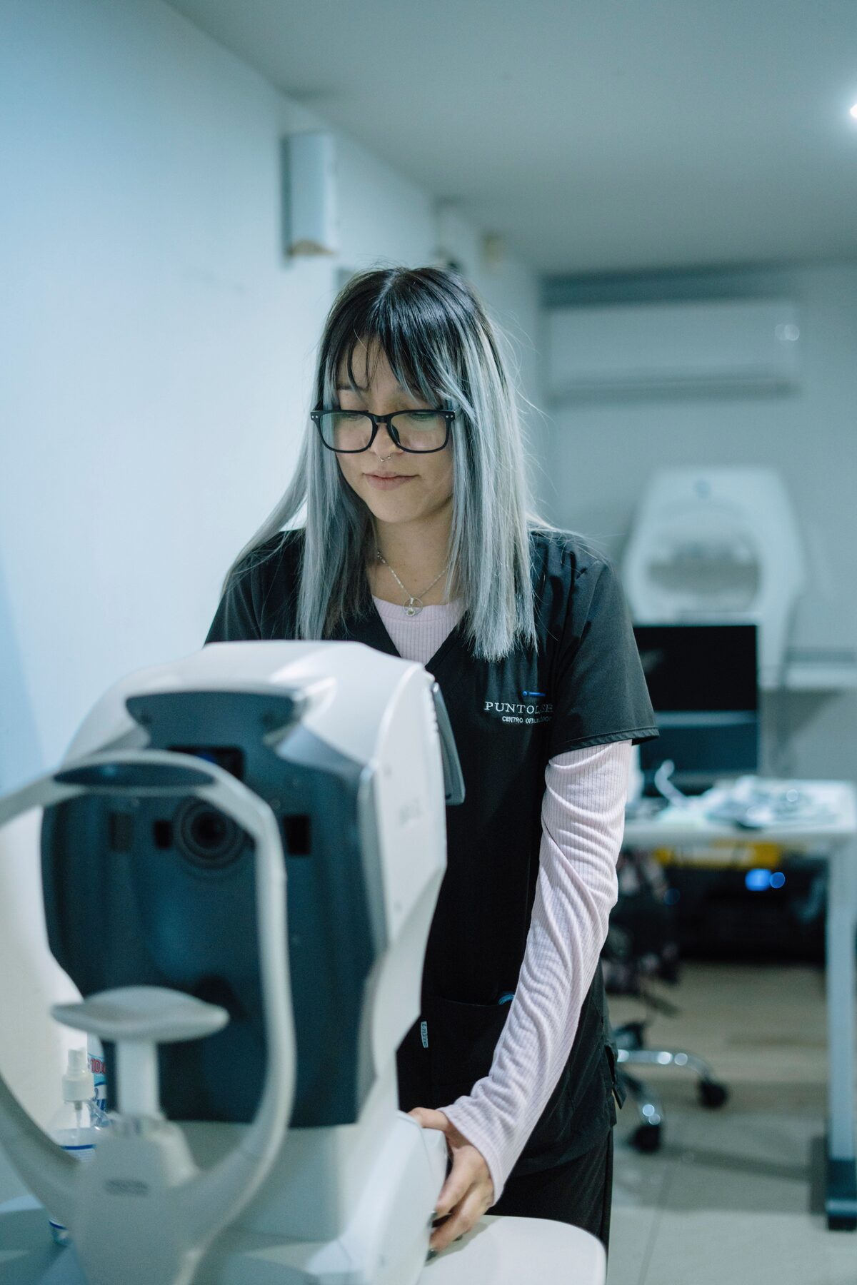 A gray-haired clinician works with eye examination equipment.